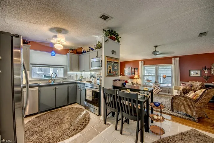 Kitchen with gray cabinets, appliances with stainless steel finishes, a textured ceiling, and sink