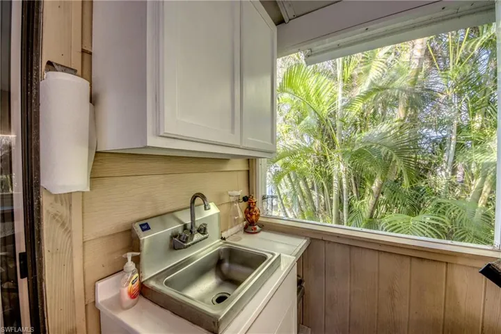 Kitchen with white cabinets, wood walls, and sink