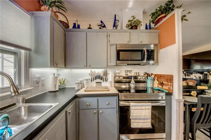 Kitchen with gray cabinetry, sink, a textured ceiling, and appliances with stainless steel finishes