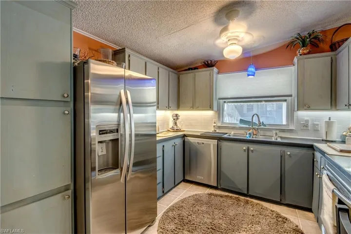 Kitchen featuring light tile patterned flooring, gray cabinetry, sink, and appliances with stainless steel finishes