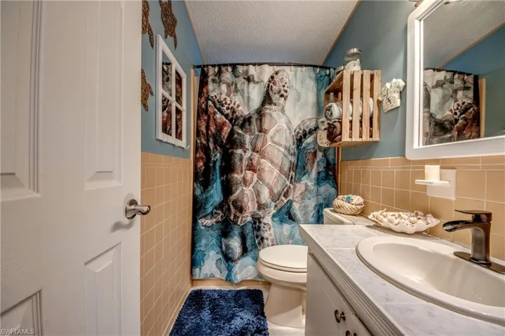 Bathroom with tile walls, vanity, a textured ceiling, and toilet