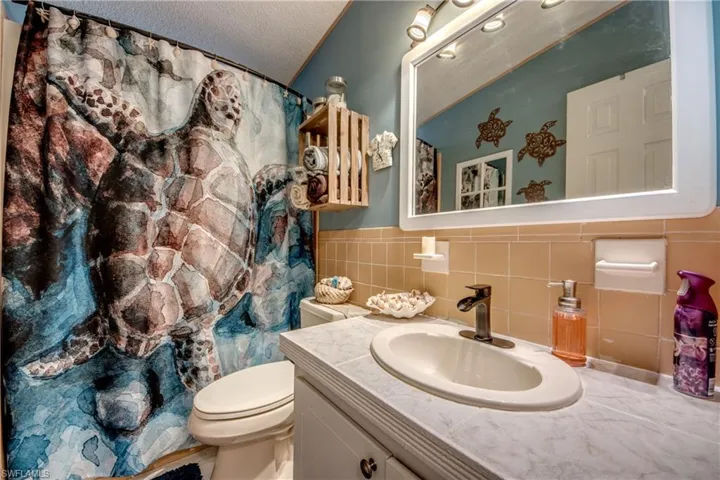 Bathroom featuring tile walls, vanity, a textured ceiling, and toilet