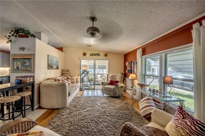 Sitting room featuring a textured ceiling, light hardwood / wood-style floors, ceiling fan, and vaulted ceiling