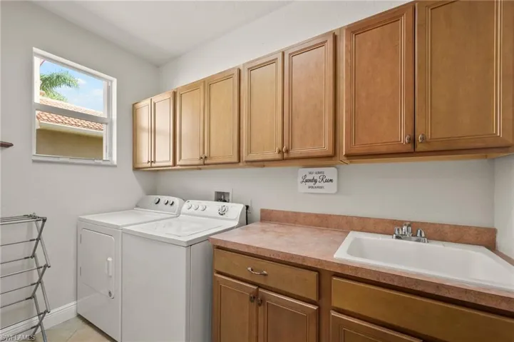 Washroom with sink, light tile patterned flooring, cabinets, and independent washer and dryer