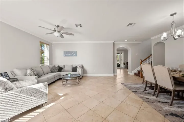 Living room featuring ceiling fan with notable chandelier and crown molding