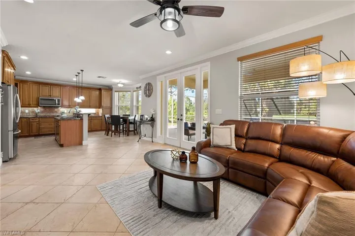 Tiled living room featuring ceiling fan, sink, crown molding, and french doors
