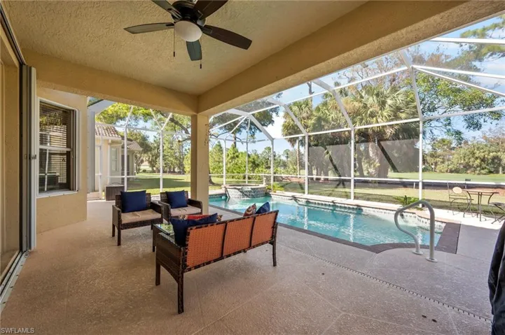 View of swimming pool featuring ceiling fan, an outdoor hangout area, a patio, and glass enclosure