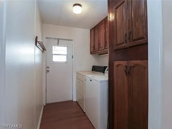 Laundry room with dark wood-type flooring, independent washer and dryer, and cabinet space
