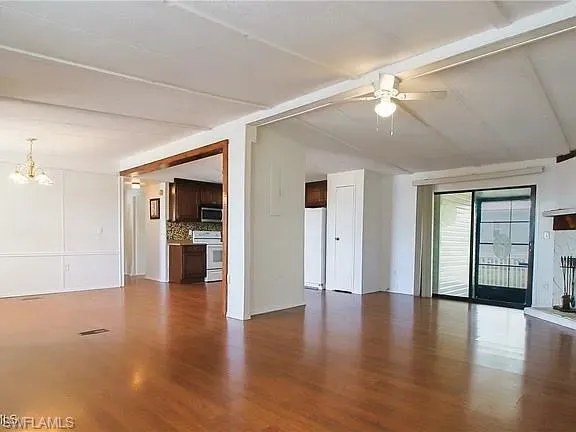 Unfurnished living room with wood finished floors, a chandelier, and ceiling fan