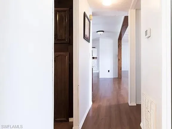 Corridor featuring dark wood-style flooring and baseboards
