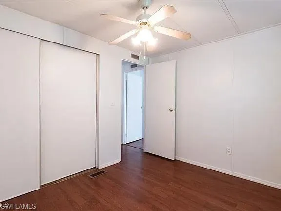 Unfurnished bedroom featuring dark wood-style flooring, ceiling fan, and a closet