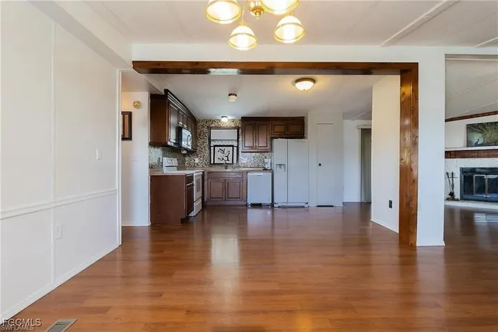 Kitchen with light countertops, white appliances, dark wood-type flooring, open floor plan, and a chandelier