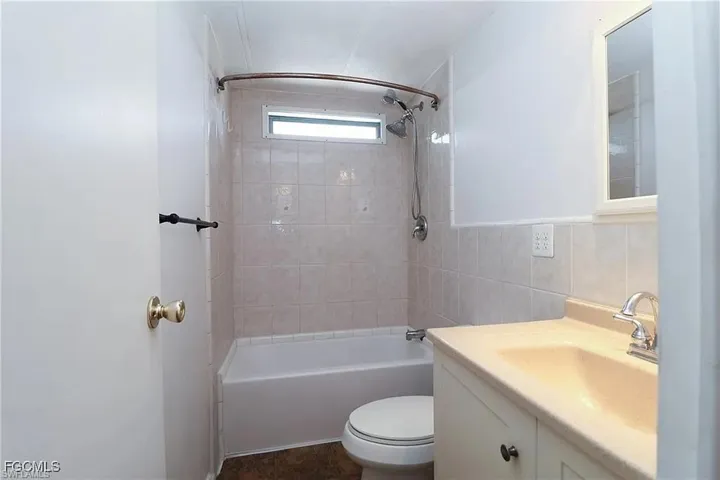 Full bath with tub / shower combination, vanity, and tile walls