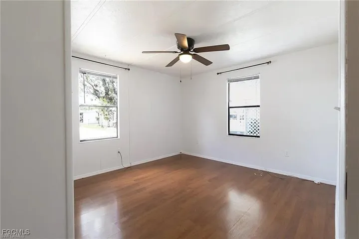 Unfurnished room with dark wood-type flooring and ceiling fan