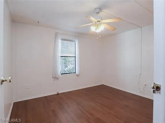 Unfurnished room featuring dark wood-type flooring and ceiling fan