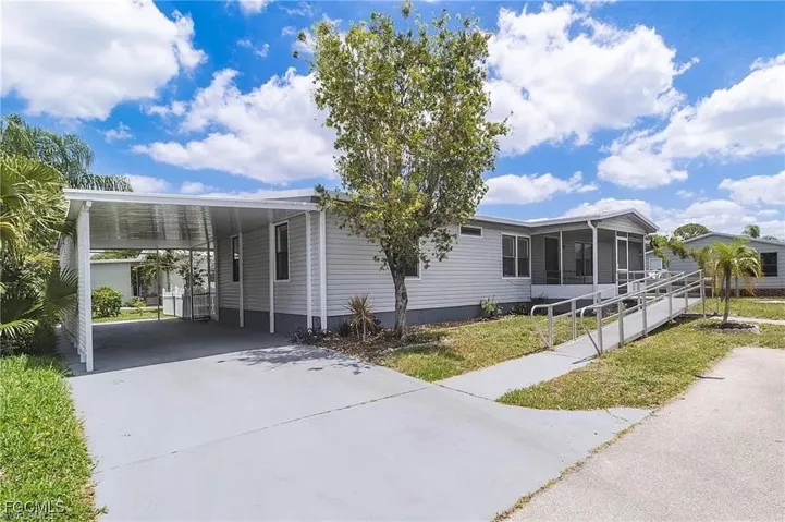Manufactured / mobile home featuring a sunroom, concrete driveway, and a carport