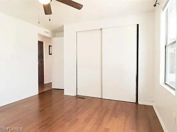 Unfurnished bedroom featuring wood finished floors, a ceiling fan, and a closet