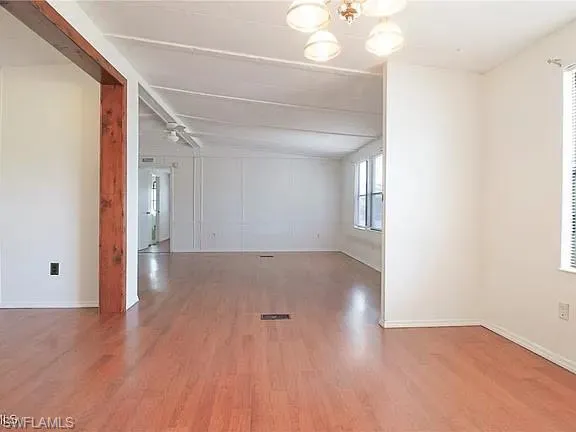 Empty room with light wood-style floors and a chandelier