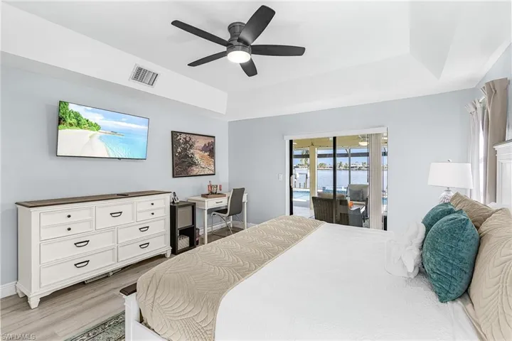 Primary Bedroom with desk, tv and slider to pool