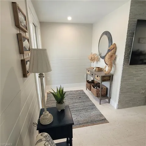 Living area featuring light floors, a wainscoted wall, ceiling fan, and tile accent wall.