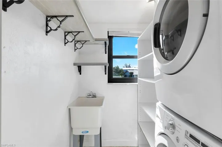 Washroom with stacked washer / drying machine and sink