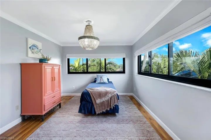 Bedroom with wood-type flooring, ornamental molding, and an inviting chandelier