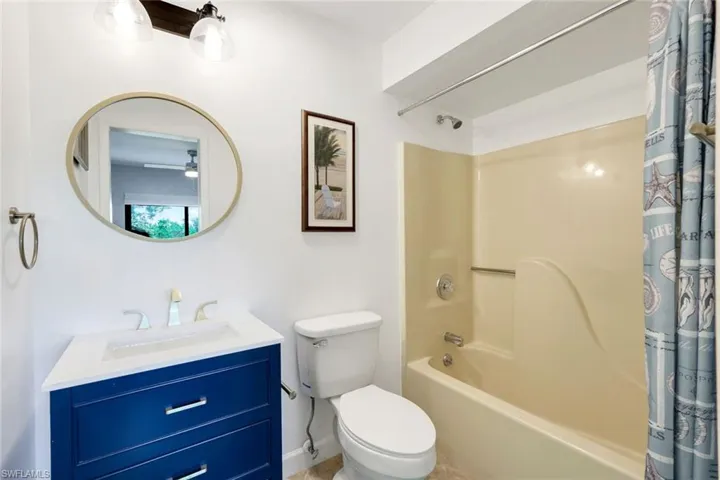 Full bathroom featuring shower / bath combination with curtain, vanity, and toilet