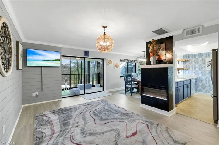 Living room featuring sink, light hardwood / wood-style flooring, crown molding, and an inviting chandelier
