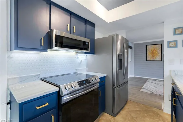 Kitchen with light stone counters, stainless steel appliances, light wood-type flooring, and blue cabinets