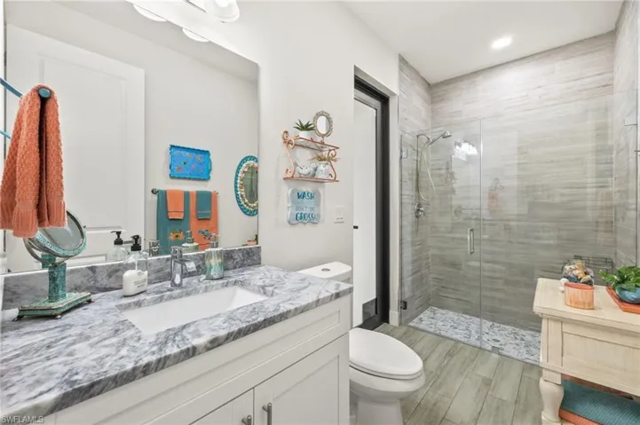 Bathroom with vanity, a stall shower, wood finished floors, and recessed lighting