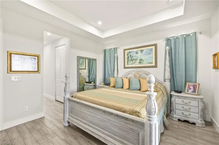 Bedroom featuring light wood-style floors, a raised ceiling, and recessed lighting