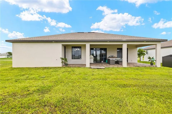 Rear view of house with outdoor lounge area, a patio, stucco siding, a lawn, and roof with shingles