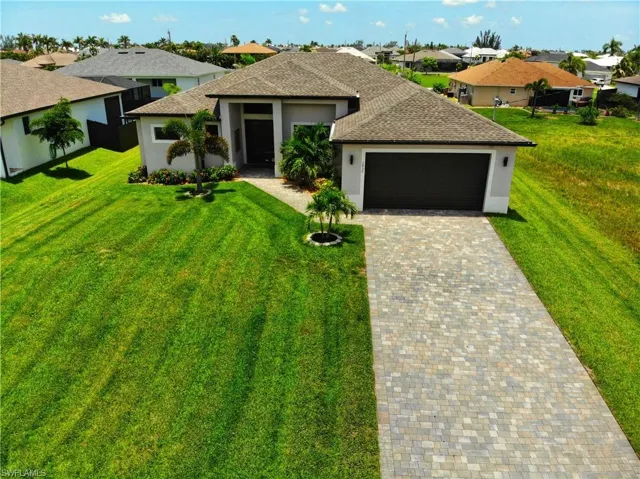 View of front of house with a garage, stucco siding, a shingled roof, decorative driveway, and a front lawn