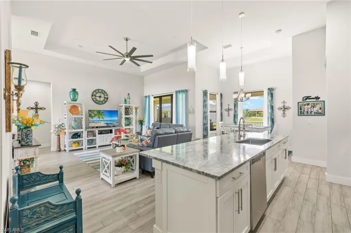 Kitchen featuring a raised ceiling, ceiling fan, light wood-style floors, and open floor plan