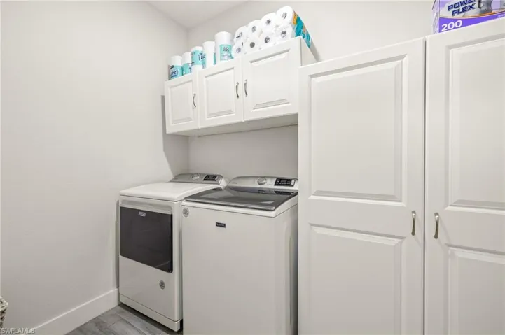 Laundry area featuring separate washer and dryer, cabinet space, and light wood-style flooring