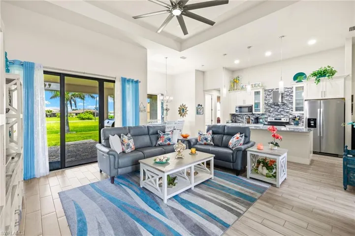 Living area featuring a ceiling fan, a chandelier, light wood-style flooring, recessed lighting, and a high ceiling