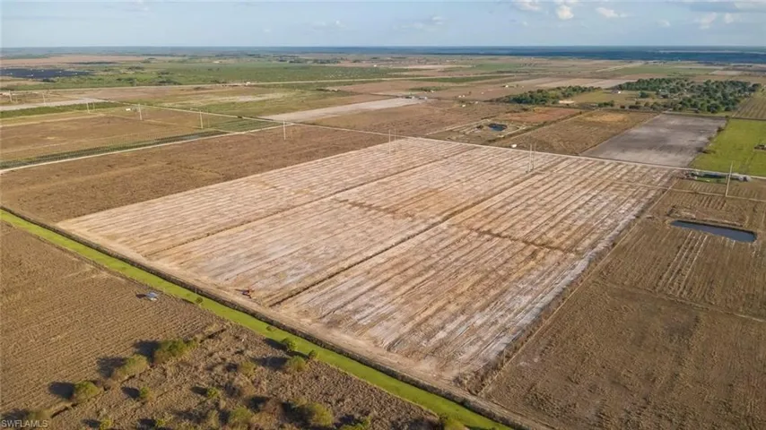 Expansive agricultural land featuring multiple cultivated fields and a drainage canal