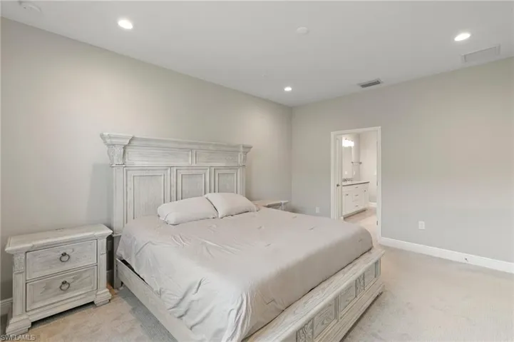 Bedroom with light carpet, recessed lighting, and ensuite bathroom