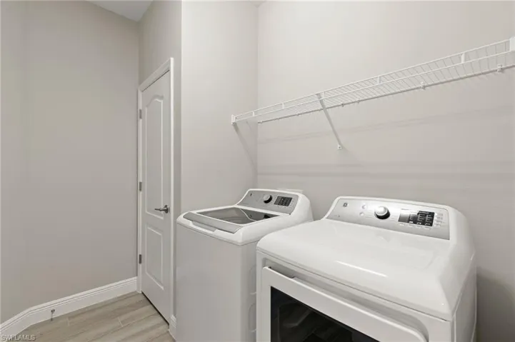 Laundry area with washer and dryer and light wood-style flooring