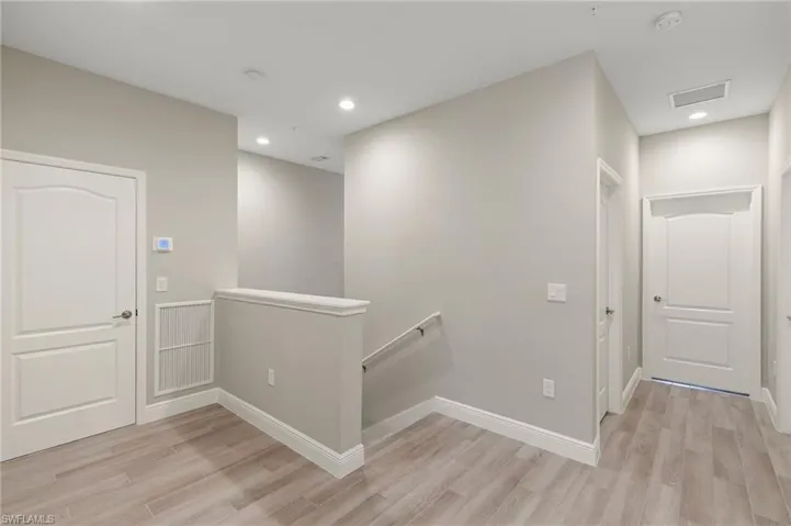 Corridor with an upstairs landing, light wood-type flooring, and recessed lighting