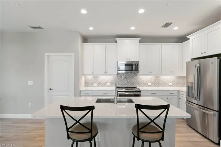 Kitchen with appliances with stainless steel finishes, backsplash, a kitchen breakfast bar, and recessed lighting