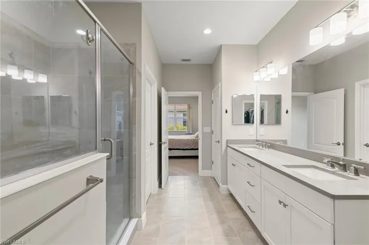 Full bath with double vanity, a stall shower, ensuite bathroom, recessed lighting, and tile patterned flooring