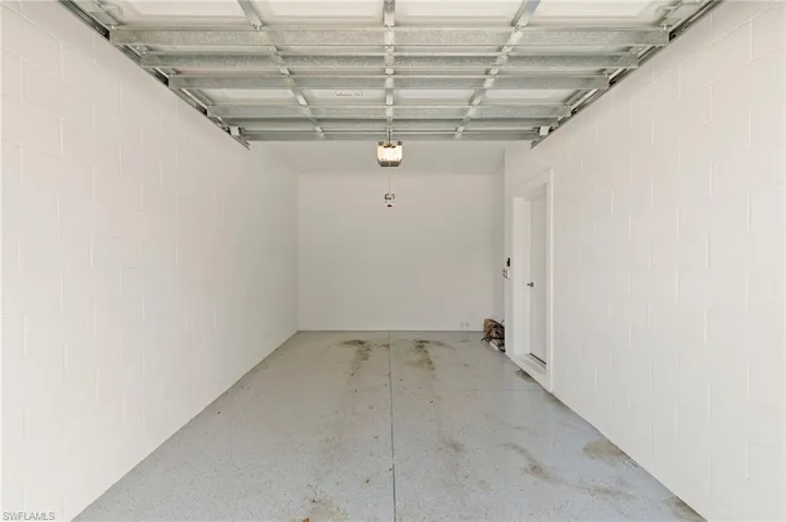 Garage featuring a garage door opener and concrete block wall
