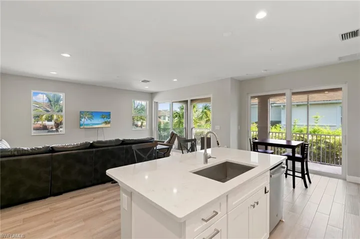 Kitchen with stainless steel dishwasher, open floor plan, light stone countertops, recessed lighting, and light wood-style flooring
