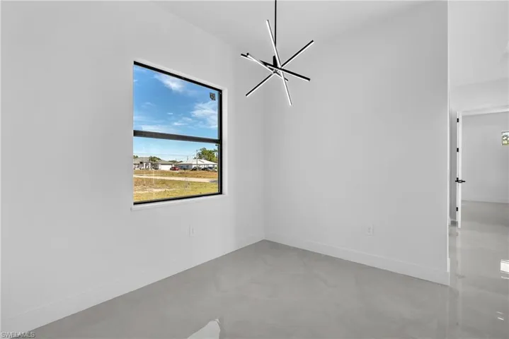 Spare room featuring baseboards and a chandelier