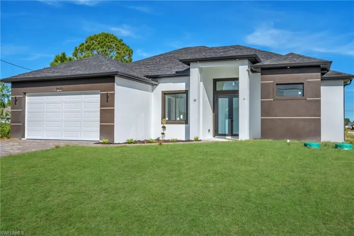 Prairie-style home with stucco siding, a front yard, an attached garage, and driveway