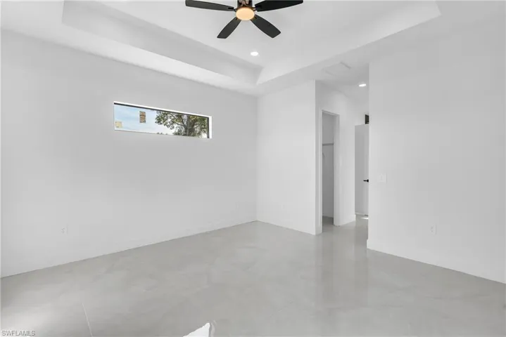 Empty room with a tray ceiling, recessed lighting, and a ceiling fan