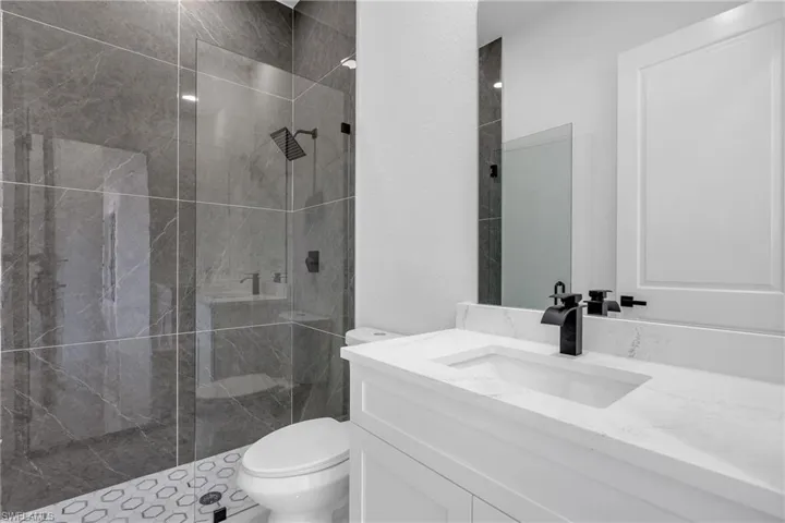Full bathroom featuring a marble finish shower and vanity
