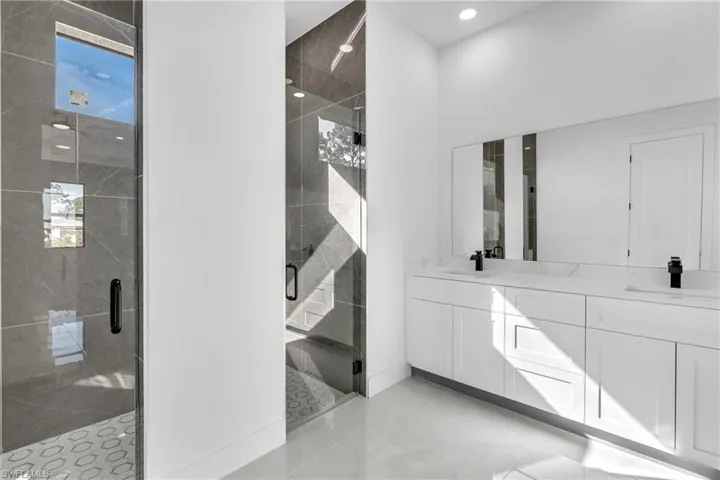 Full bath with a stall shower, double vanity, and light tile patterned floors