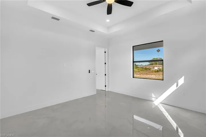 Empty room featuring a raised ceiling, recessed lighting, and a ceiling fan